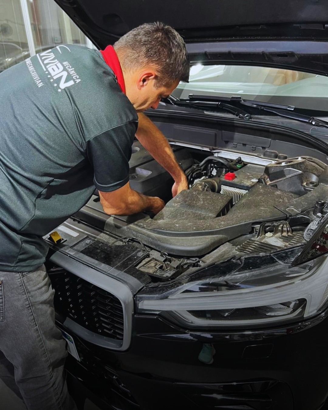 Mecânico da Mecânica Vivian inspecionando o motor de um veículo